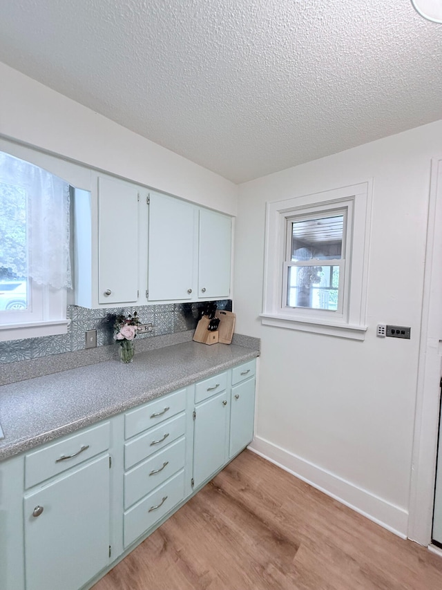 3628 Rau Rd, West Branch, MI 48661 - kitchen with light wood finished floors, tasteful backsplash, a textured ceiling, and light countertops