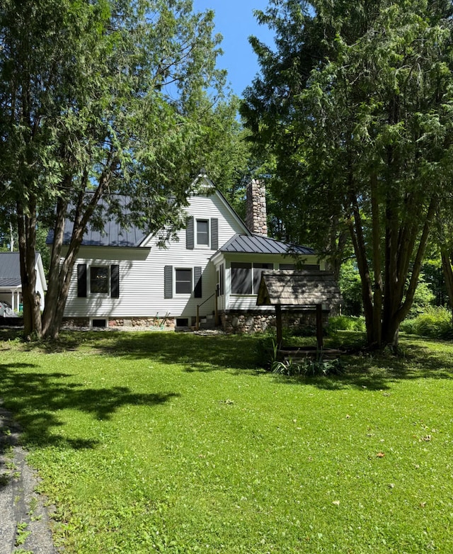 3628 Rau Rd, West Branch, MI 48661 - back of property with a chimney, a yard, a sunroom, and a standing seam roof