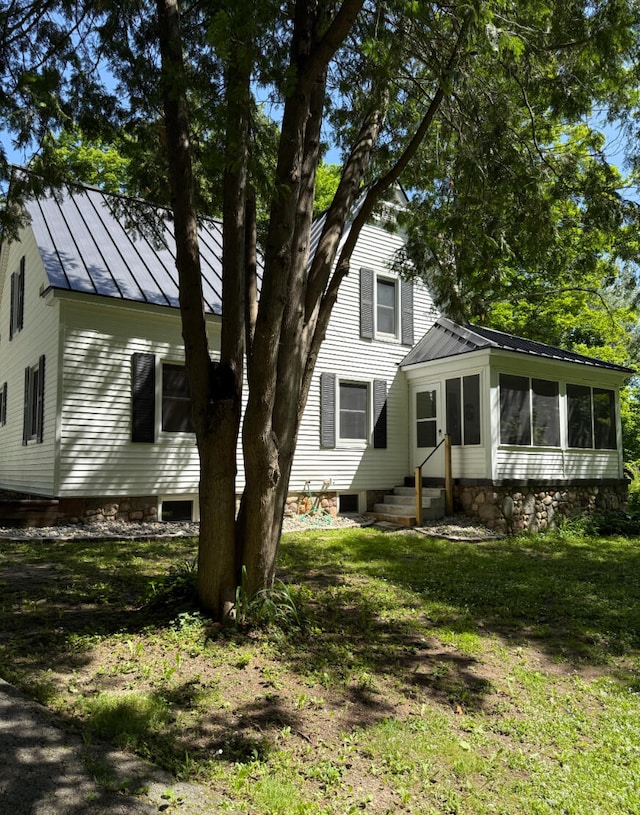 3628 Rau Rd, West Branch, MI 48661 - view of front facade featuring a sunroom, a standing seam roof, a metal roof, a front yard, and entry steps