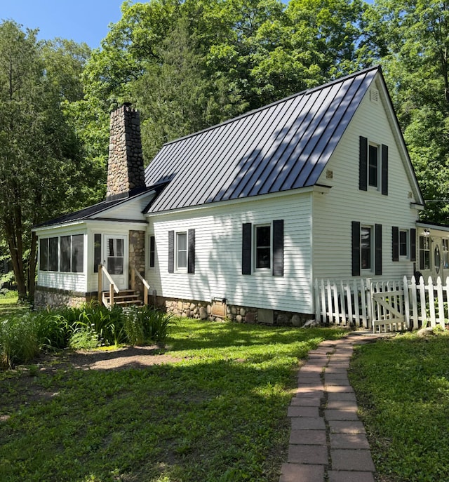 3628 Rau Rd, West Branch, MI 48661 - view of front of house featuring a standing seam roof, entry steps, a chimney, a metal roof, and a sunroom