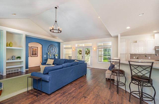 118 Frisco Dr, Houghton Lake, MI 48629 - living room with vaulted ceiling, dark wood-type flooring, a chandelier, built in features, and arched walkways