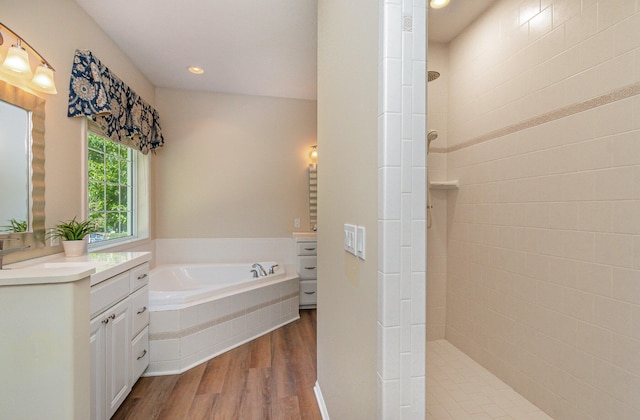 118 Frisco Dr, Houghton Lake, MI 48629 - full bathroom featuring vanity, wood finished floors, walk in shower, a garden tub, and recessed lighting