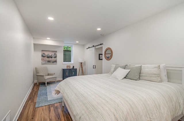 118 Frisco Dr, Houghton Lake, MI 48629 - bedroom with a barn door, dark wood-style flooring, and recessed lighting