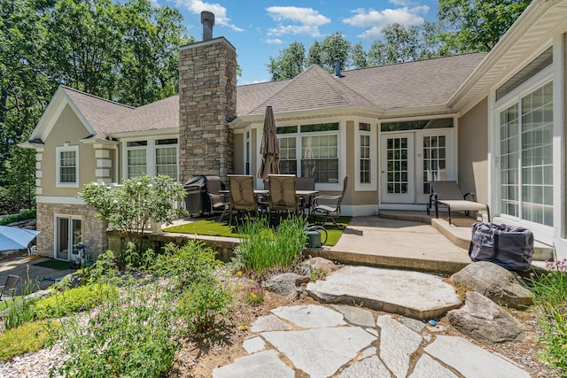 118 Frisco Dr, Houghton Lake, MI 48629 - back of house featuring a patio, roof with shingles, a chimney, and stucco siding