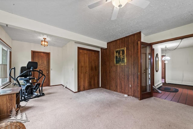 2801 Cobb Rd, Lewiston, MI 49756 - workout room featuring carpet, baseboard heating, ceiling fan, wooden walls, and a textured ceiling