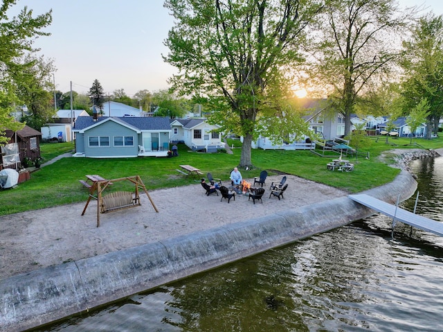 6390 W Houghton Lake Dr, Houghton Lake, MI 48629 - rear view of house featuring a fire pit, a water view, and a lawn