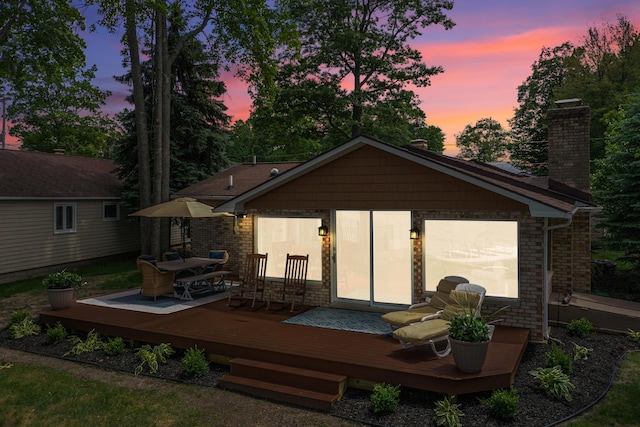 802 Houghton View Dr, Prudenville, MI 48651 - back of house at dusk with a chimney and a wooden deck