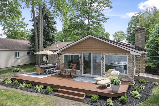 802 Houghton View Dr, Prudenville, MI 48651 - rear view of house featuring a chimney, outdoor dining space, and a wooden deck