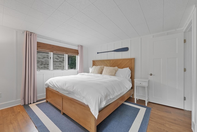 802 Houghton View Dr, Prudenville, MI 48651 - bedroom featuring wood finished floors and a decorative wall