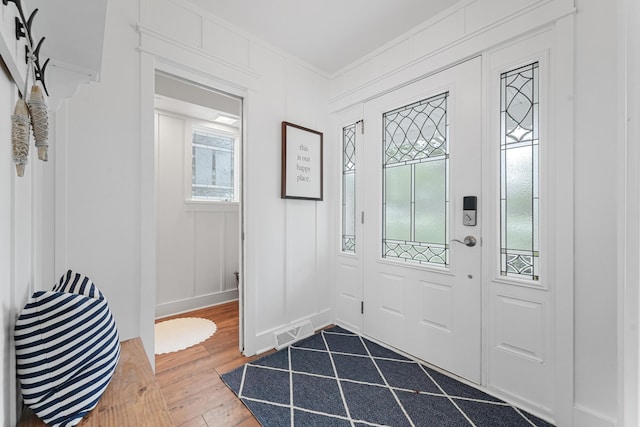 802 Houghton View Dr, Prudenville, MI 48651 - entryway with dark wood-style floors, crown molding, and a decorative wall