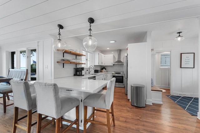 802 Houghton View Dr, Prudenville, MI 48651 - kitchen featuring appliances with stainless steel finishes, wall chimney range hood, backsplash, open shelves, and a kitchen breakfast bar