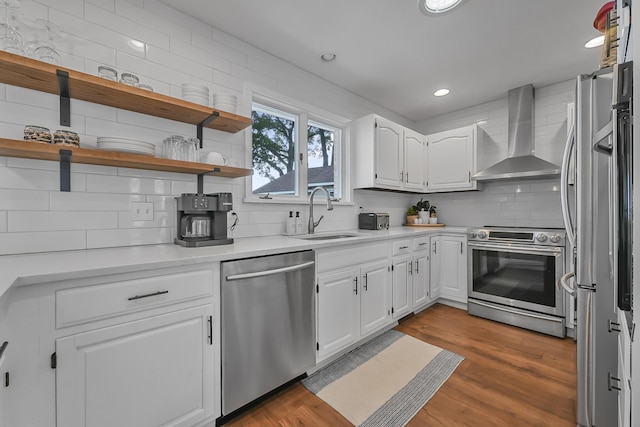 802 Houghton View Dr, Prudenville, MI 48651 - kitchen with stainless steel appliances, wall chimney exhaust hood, decorative backsplash, white cabinets, and wood finished floors