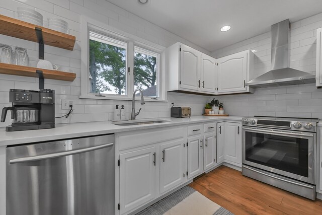 802 Houghton View Dr, Prudenville, MI 48651 - kitchen with stainless steel appliances, wall chimney exhaust hood, backsplash, light countertops, and recessed lighting