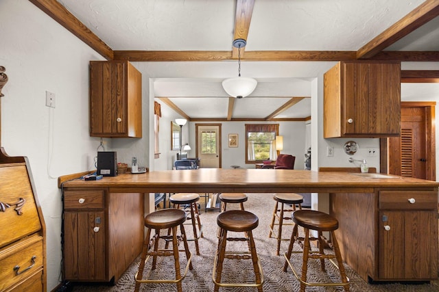 6612 Old Vanderbilt Rd, Vanderbilt, MI 49795 - kitchen featuring beamed ceiling, a breakfast bar area, brown cabinets, and an office area