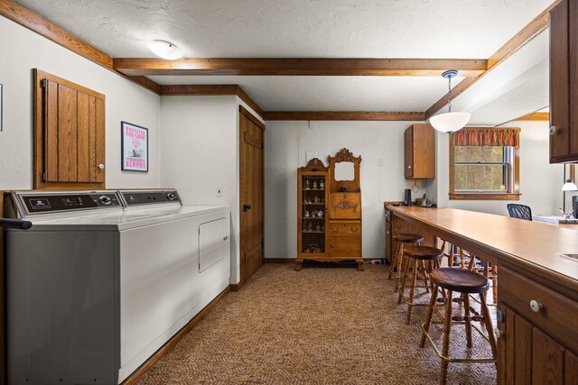 6612 Old Vanderbilt Rd, Vanderbilt, MI 49795 - kitchen featuring washer and dryer, beam ceiling, brown cabinets, carpet floors, and decorative light fixtures