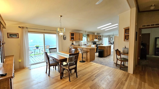 7717 Weiss Rd, Alpena, MI 49707 - dining area featuring light wood-type flooring, a chandelier, ornamental molding, and a skylight