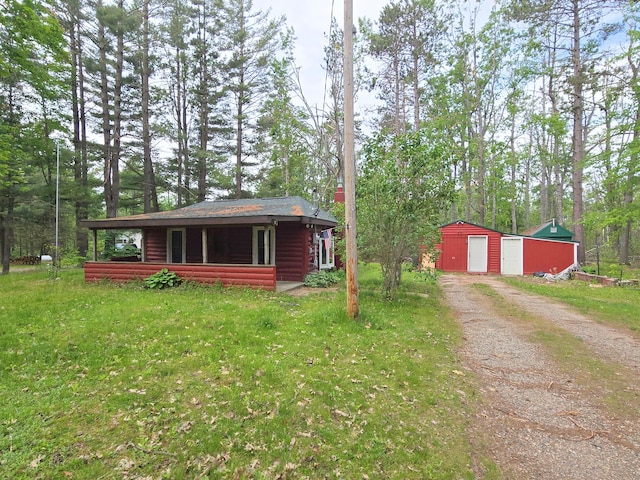 2880 Ann Arbor Rd, Lewiston, MI 49756 - view of front facade featuring dirt driveway, an outbuilding, a detached garage, and a front yard
