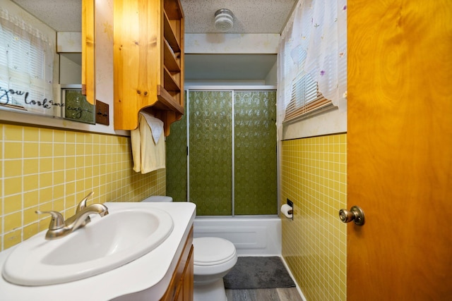 2731 Gregory St, Lewiston, MI 49756 - bathroom with tile walls, vanity, bath / shower combo with glass door, wood finished floors, and wainscoting