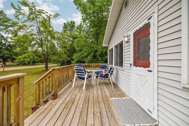 2731 Gregory St, Lewiston, MI 49756 - wooden terrace with outdoor dining area, view of wooded area, and a lawn