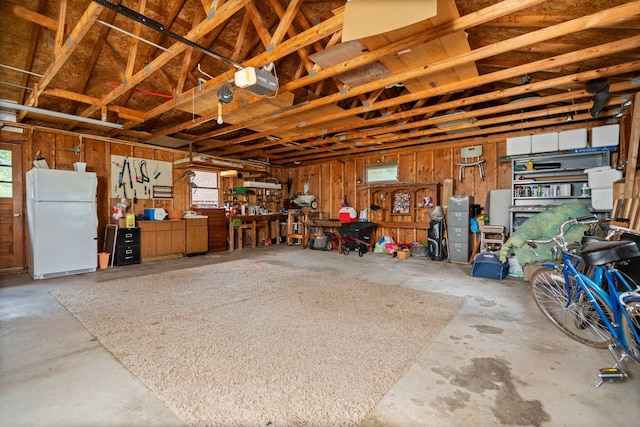 2731 Gregory St, Lewiston, MI 49756 - garage with freestanding refrigerator, a garage door opener, and a workshop area