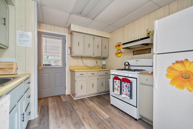 2731 Gregory St, Lewiston, MI 49756 - kitchen with white appliances, premium range hood, a paneled ceiling, wooden walls, and light countertops