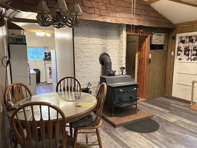 16831 Moores Landing Rd, Lachine, MI 49753 - dining area featuring a wood stove, lofted ceiling, wood finished floors, and a chandelier