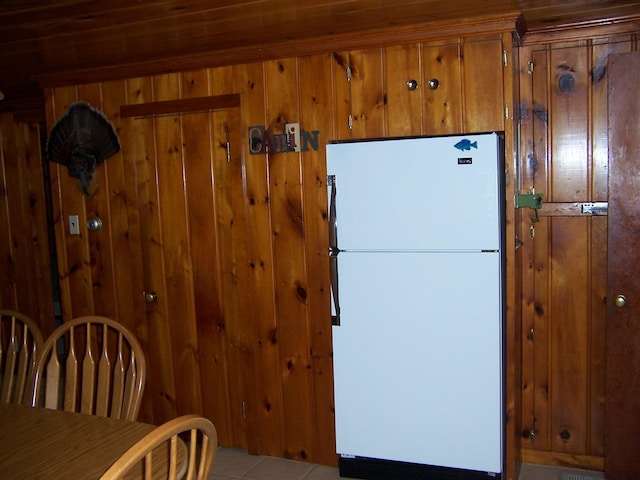 409 Marvin Rd, Roscommon, MI 48653 - kitchen featuring freestanding refrigerator, brown cabinetry, tile patterned floors, and wooden walls