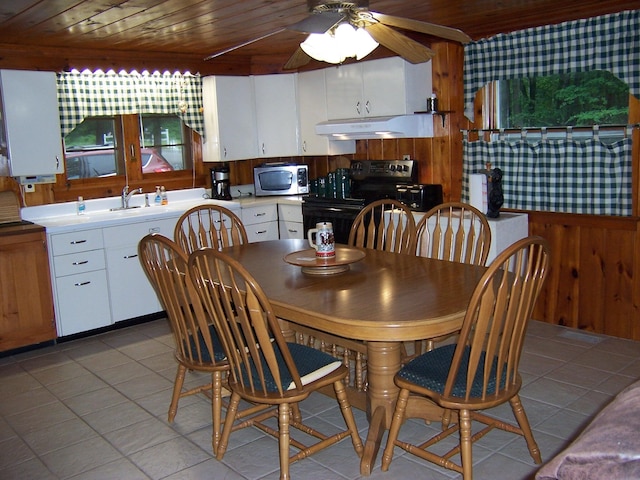 409 Marvin Rd, Roscommon, MI 48653 - dining space with wood ceiling, wooden walls, light tile patterned floors, and a ceiling fan