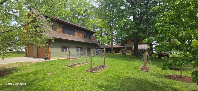 1161 Lagoon St, Lewiston, MI 49756 - view of grassy yard with driveway, a garage, and a vegetable garden