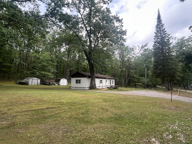 15939 Hiawatha Trl, Atlanta, MI 49709 - view of grassy yard with a storage unit and a view of trees