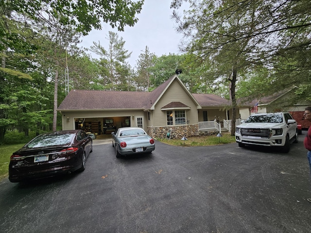 14911 Kings Ln, Ocqueoc, MI 49759 - single story home with driveway, an attached garage, a porch, and stone siding