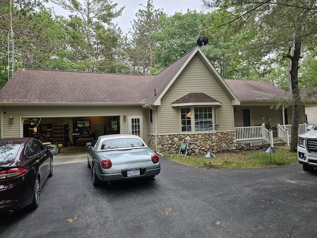 14911 Kings Ln, Ocqueoc, MI 49759 - ranch-style house with asphalt driveway, roof with shingles, a garage, and stone siding