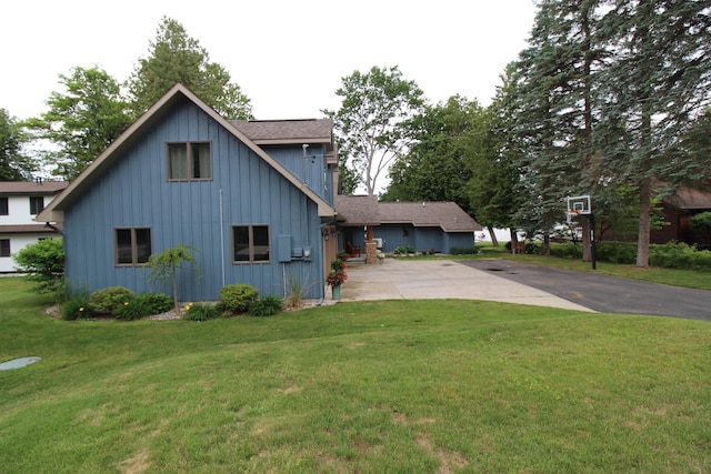2150 Danish Landing Rd, Grayling, MI 49738 - view of side of home with board and batten siding, driveway, roof with shingles, and a lawn