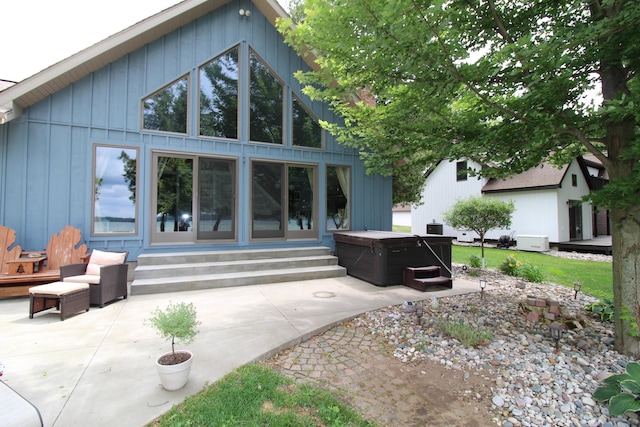 2150 Danish Landing Rd, Grayling, MI 49738 - back of house with a hot tub, a patio area, and board and batten siding