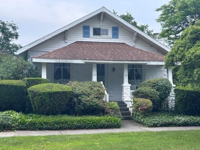 108 Potter St, Alpena, MI 49707 - view of front of property featuring a shingled roof, a porch, and stucco siding