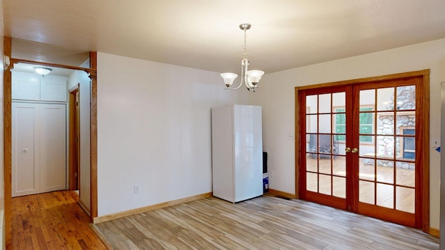 7090 Nancy K Dr, Hale, MI 48739 - unfurnished dining area with french doors, light wood-type flooring, and a chandelier