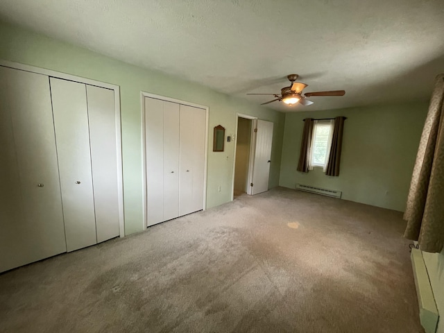982 Shaggy Bark Ct, Gaylord, MI 49735 - unfurnished bedroom featuring a baseboard radiator, two closets, carpet, and ceiling fan