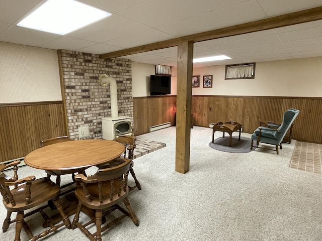 982 Shaggy Bark Ct, Gaylord, MI 49735 - carpeted dining space featuring a wainscoted wall, a wood stove, a paneled ceiling, baseboard heating, and wooden walls