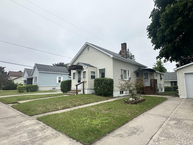 711 S 8th Ave, Alpena, MI 49707 - bungalow-style house featuring a chimney, a front lawn, a garage, and an outbuilding