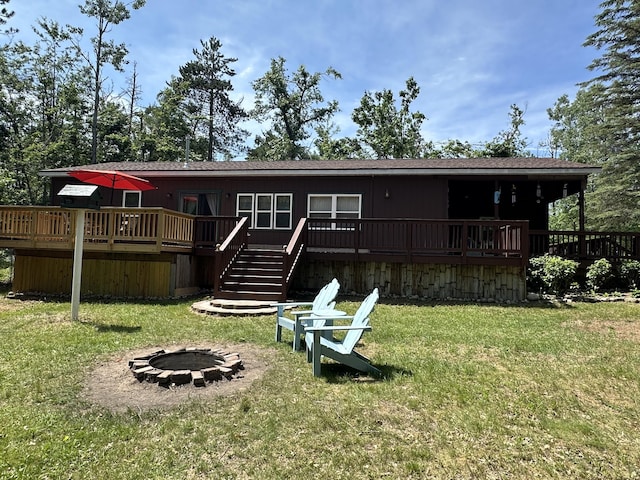 5127 Crestwood Rd, Lewiston, MI 49756 - rear view of house featuring a fire pit, a wooden deck, and a lawn