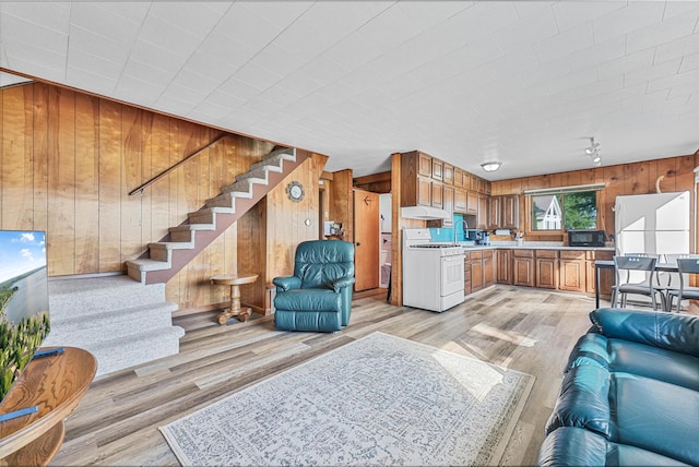 12328 W Shore Dr, Houghton Lake, MI 48629 - living room with wood walls, light wood-style floors, and stairs