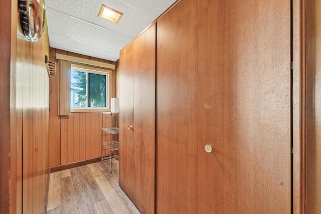12328 W Shore Dr, Houghton Lake, MI 48629 - hallway featuring light wood-type flooring, wooden walls, and a textured ceiling