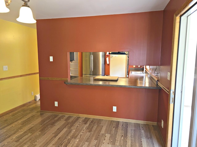 N705 Woods Rd, Saint Ignace, MI 49781 - kitchen with freestanding refrigerator, wood finished floors, a baseboard radiator, and a peninsula