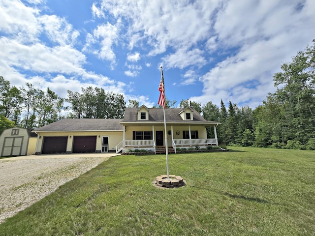 N705 Woods Rd, Saint Ignace, MI 49781 - view of front of home with covered porch, a storage shed, an attached garage, gravel driveway, and a front lawn