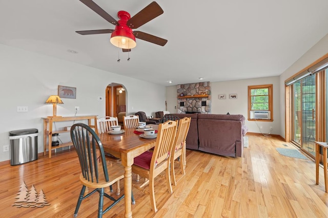6609 Honey Ln, Johannesburg, MI 49751 - dining room with arched walkways, light wood-style flooring, ceiling fan, cooling unit, and a fireplace