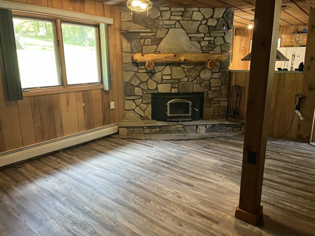 2359 Watson Hills Trl, Vanderbilt, MI 49795 - unfurnished living room with wood walls, a baseboard heating unit, wood finished floors, and a fireplace