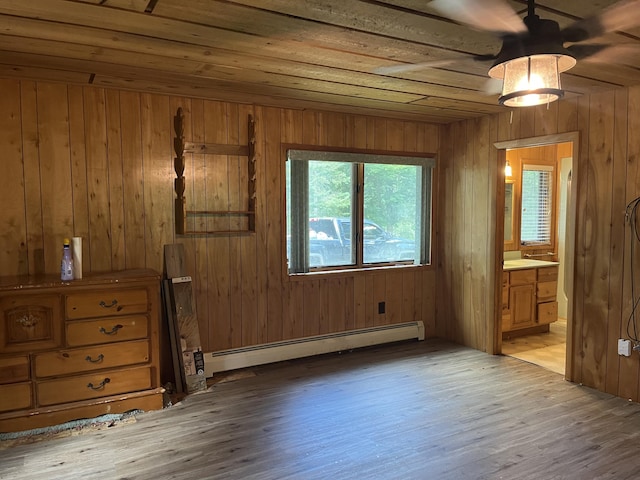 2359 Watson Hills Trl, Vanderbilt, MI 49795 - unfurnished bedroom featuring a baseboard radiator, light wood-style flooring, wood walls, and ensuite bath