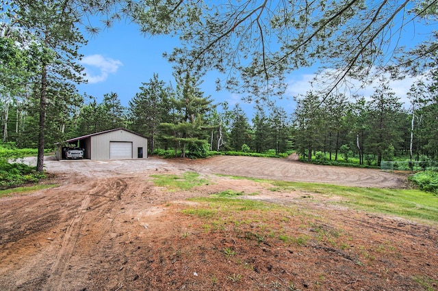 6691 Boone Ln, Vanderbilt, MI 49795 - view of yard featuring dirt driveway, a detached garage, an outbuilding, and a wooded view