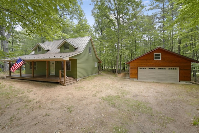 120 Clyde St, Roscommon, MI 48653 - view of side of home featuring a detached garage, covered porch, a metal roof, and an outbuilding