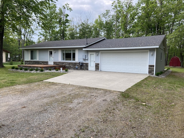 3350 Woodcrest Dr, Lewiston, MI 49756 - ranch-style house featuring concrete driveway, stone siding, a garage, roof with shingles, and a front yard